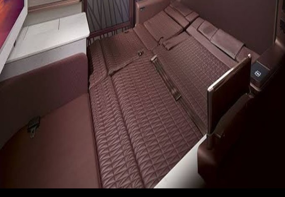 JAL Suite Life first class seat fully reclined into a flat bed, oxblood quilted leather